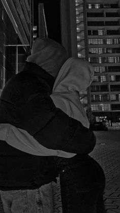 a person sitting on a bench in front of a building at night with their back to the camera