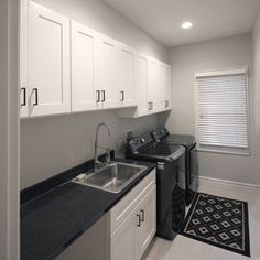 a kitchen with white cabinets and black counter tops next to a washer and dryer