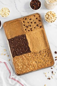 a baking pan filled with cookies and chocolate chips on top of a white marble counter