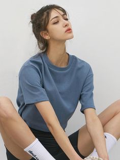 a woman sitting on the ground with her legs crossed wearing tennis shoes and knee socks