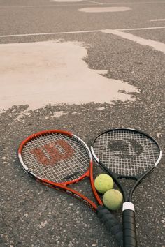 a tennis racket and two balls on the ground