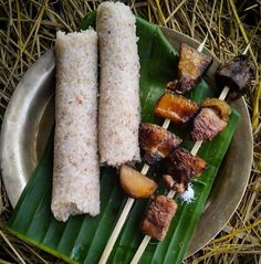 some food is sitting on top of a leafy green plate with chopsticks