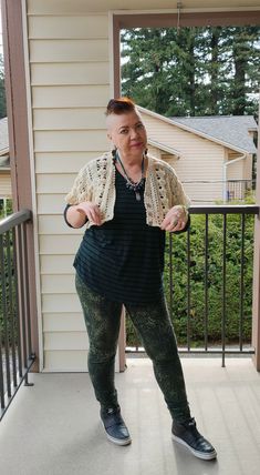 a woman standing on a porch with her hands in the air and looking at the camera