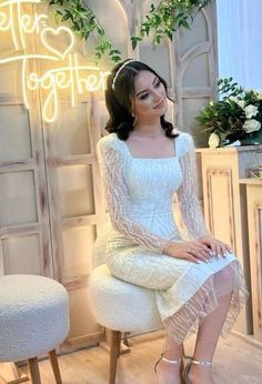 a woman sitting on top of a white chair in front of a sign that says hello together