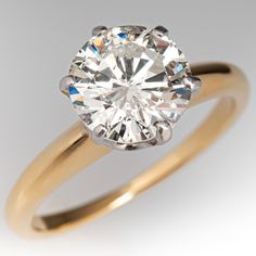 a yellow gold engagement ring with a round brilliant cut diamond in the center, on a white background