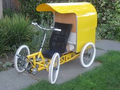 a yellow bike with a side car attached to the back is parked in front of some bushes