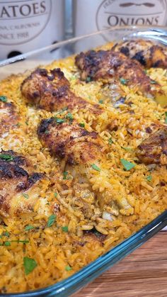 a casserole dish with chicken and rice on a table next to two cans of wine