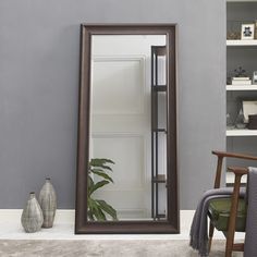 a large mirror sitting on top of a floor next to a chair