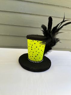 a yellow top hat with black feathers on a white table