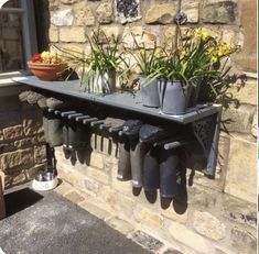 there is a shelf with some flowers and rain boots hanging from it's sides