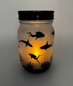 a mason jar with an underwater scene painted on the lid and light in the bottom