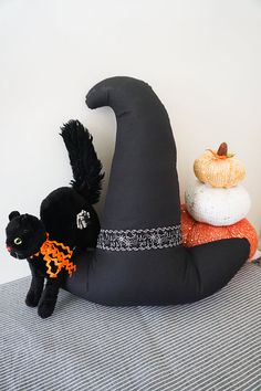 a black cat sitting on top of a fake witch's hat next to other stuffed animals