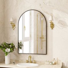 a bathroom with marble counter tops and gold fixtures on the wall, along with a round mirror