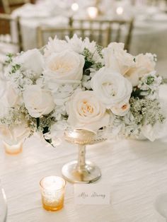 the centerpieces on this table are all white and have flowers in them, along with candles