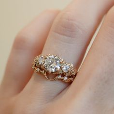 a woman's hand with a diamond ring on top of her finger and an engagement band