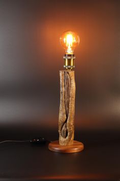 a wooden table lamp with a light bulb on it's end and a cord wrapped around the base