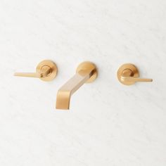 two brass handles on a white marble wall