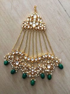 a green and white necklace with gold chains, beads and stones on it's side