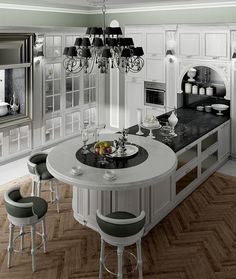 a large kitchen with white cabinets and black counter tops is pictured in this image, there are four stools at the center of the island