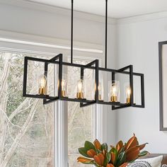 a chandelier hanging over a dining room table with flowers in the vase on it