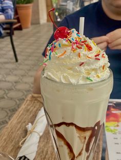 a person sitting at a table with a drink in front of them and a menu