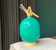 a green bottle sitting on top of a table next to a white napkin and window