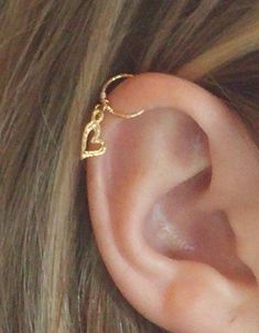 a close up of a person's ear with a gold ring on it