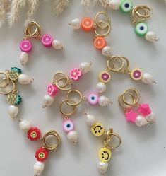 many different types of key chains on a white surface with feathers in the back ground