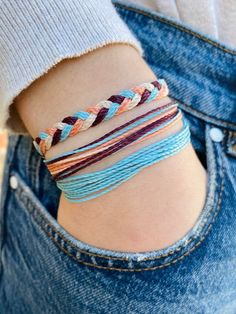 a close up of a person wearing a bracelet with different colored cords on their wrist