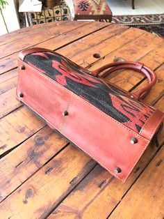 a red leather bag sitting on top of a wooden table