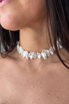 a close up of a woman wearing a white necklace with pearls on the neck and chest