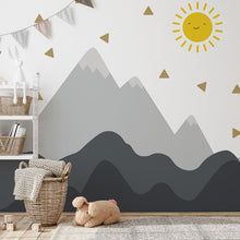 a child's room with mountains and sun decals on the wall behind it