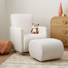 a teddy bear sitting in a white chair next to a footstool and dresser