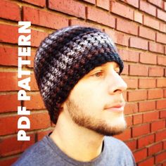 a man standing in front of a brick wall wearing a crocheted beanie