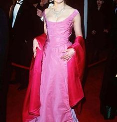 a woman in a pink dress standing on a red carpet