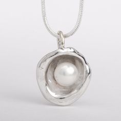 This "Aruba" pearl pendant necklace is handmade of 925 Sterling Silver. It has been hand crafted and cast in pure 92.5% solid silver in my workshop using a technique called water casting. I melt silver and pour the molten silver into cold water! The resulting organic shape creates a cup that imitates nature in a beautiful way. Finally, the lovely cultured pearl is set inside the cup to create this unique pendant.Pearl color: white Pendant size: approx 3/4 inch (20 mm) diameter The pendant hangs Handmade Silver Pearl Necklace With Round Pendant, Unique Sterling Silver Pearl Necklace Gift, Handmade Sterling Silver Pearl Pendant Necklace, Handmade Sterling Silver Pearl Necklace In Silver, Handmade Sterling Silver Pendant Pearl Necklace, Handmade Sterling Silver Pearl Necklace With Round Pendant, Silver Clay Pendant, Dark Siren, Chunky Silver Jewellery