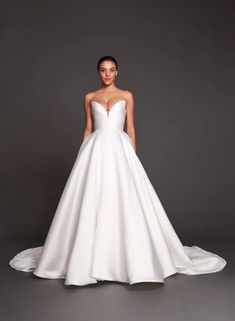 a woman in a white wedding dress standing against a gray background