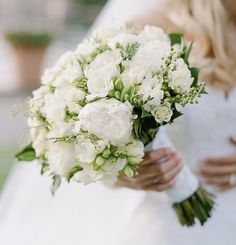 a bride holding a bouquet of white flowers