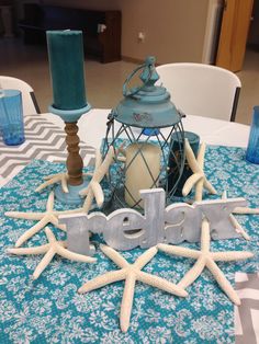 a table topped with blue candles and starfish on top of a white table cloth