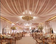 a banquet hall with tables and chairs covered in white draping, chandeliers and floral centerpieces