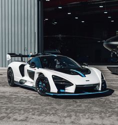 a white and blue sports car parked in front of a hangar