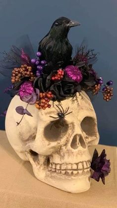 a skull with flowers in it and a crow sitting on top of it's head