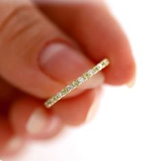 a close up of a person's hand holding a gold ring with five diamonds