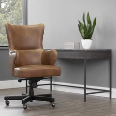 a brown leather office chair sitting in front of a desk with a potted plant