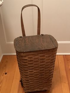 a brown basket sitting on top of a wooden floor next to a white wall and door