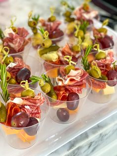 small cups filled with different types of food on top of a glass counter topped with green olives