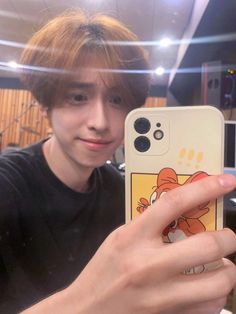 a young man taking a selfie with his cell phone in front of the camera