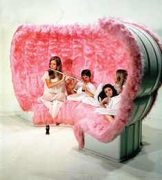 a group of women sitting on top of a giant pink object in the shape of a pig