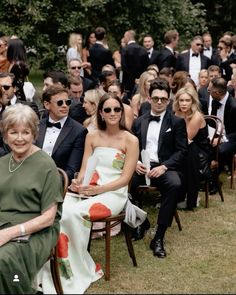 a group of people sitting next to each other on top of a grass covered field