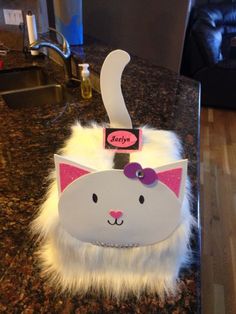 a white cat with a pink bow on it's head sitting on a counter